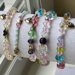 Swarovski crystal bracelets, five total, pastel colors with charms.